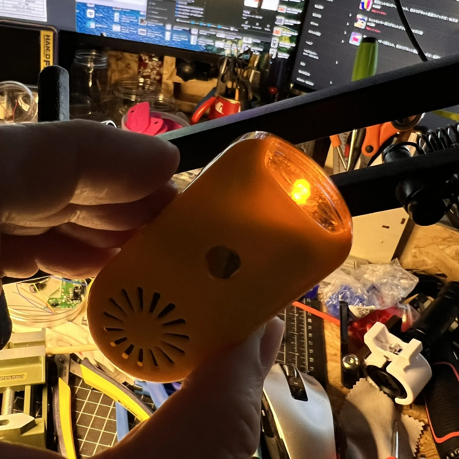 オレンジ色の本体を手に持ち、前のLEDを光らせているところ