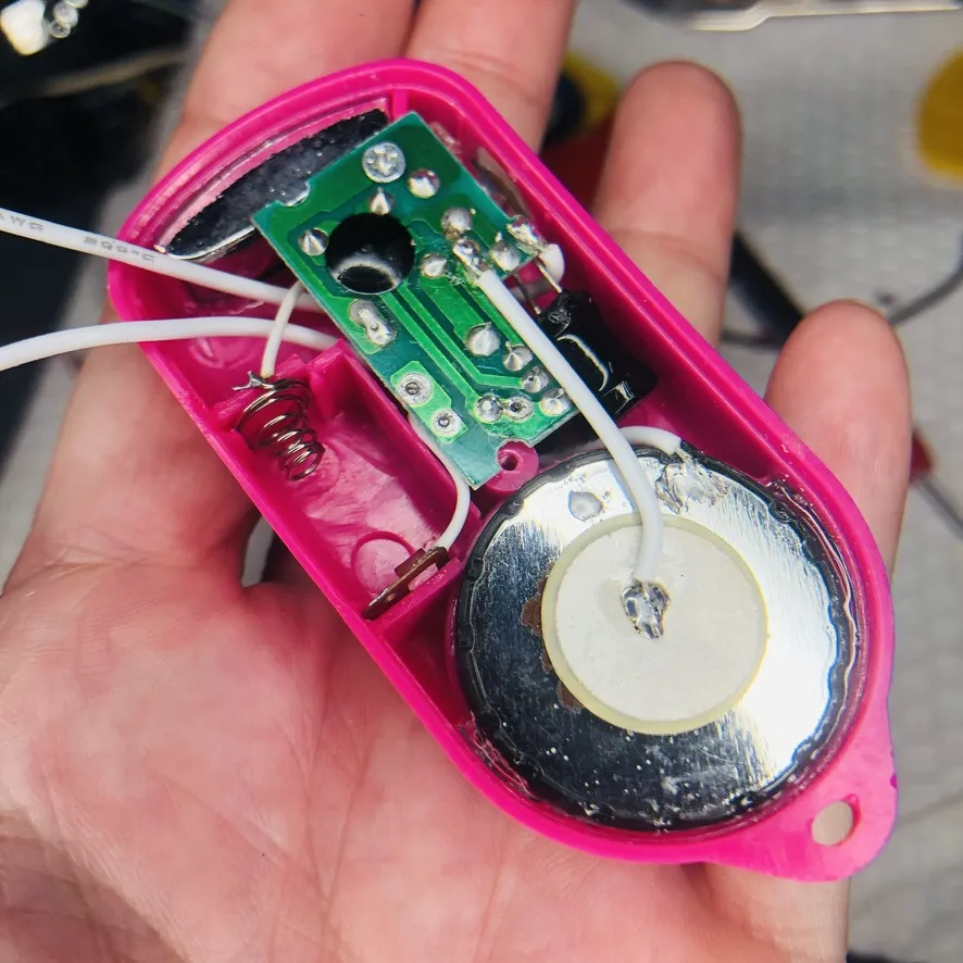 手のひらの上で開けたピンクの本体。緑の基板とスピーカーが見える