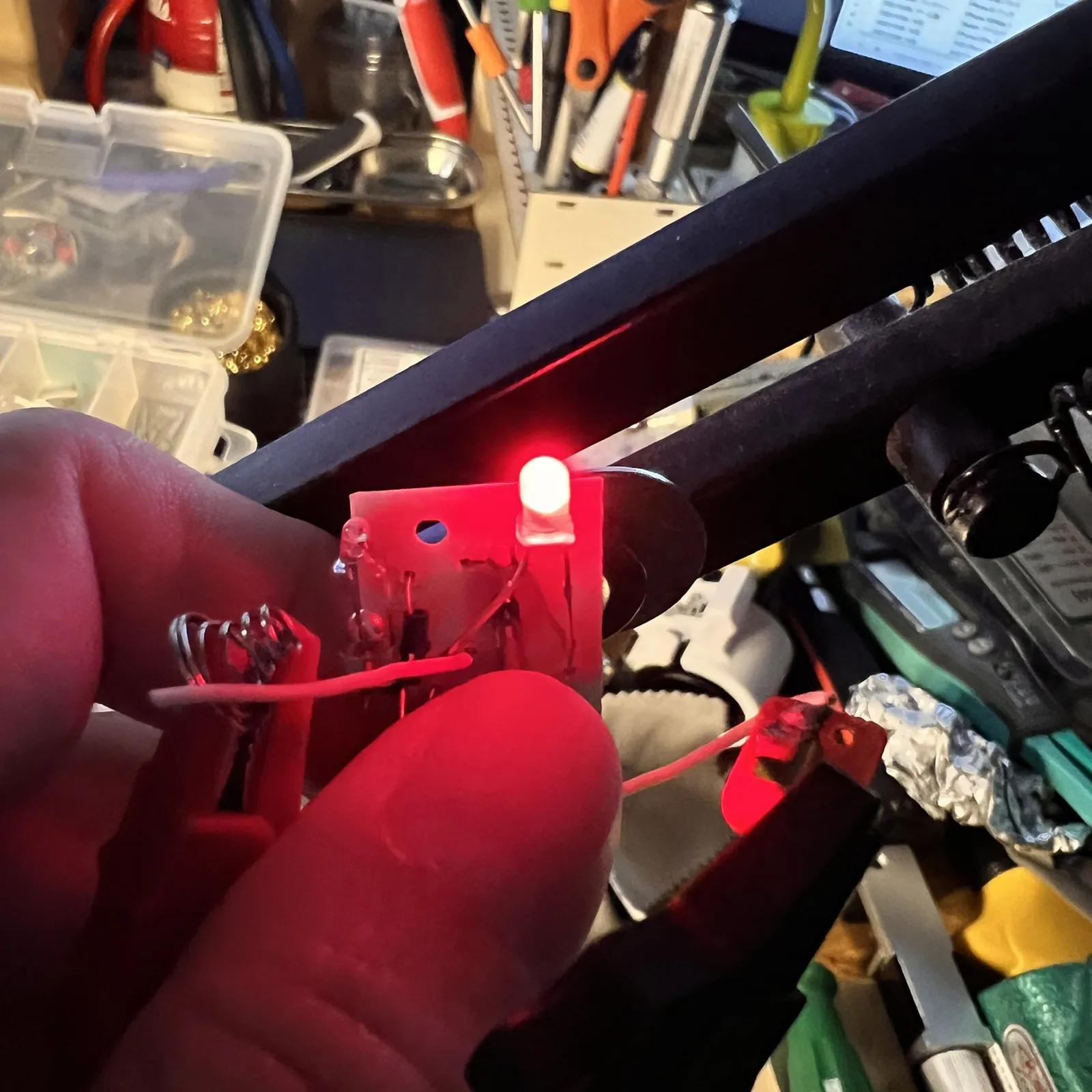 赤いLEDが光る基板を、指でつまんでいる