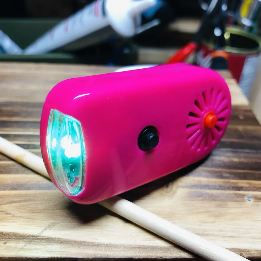 木の板の上のピンクの本体。前のLEDが光っている