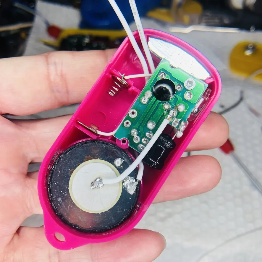 開けたピンクの本体の中。緑の基板とスピーカーと配線