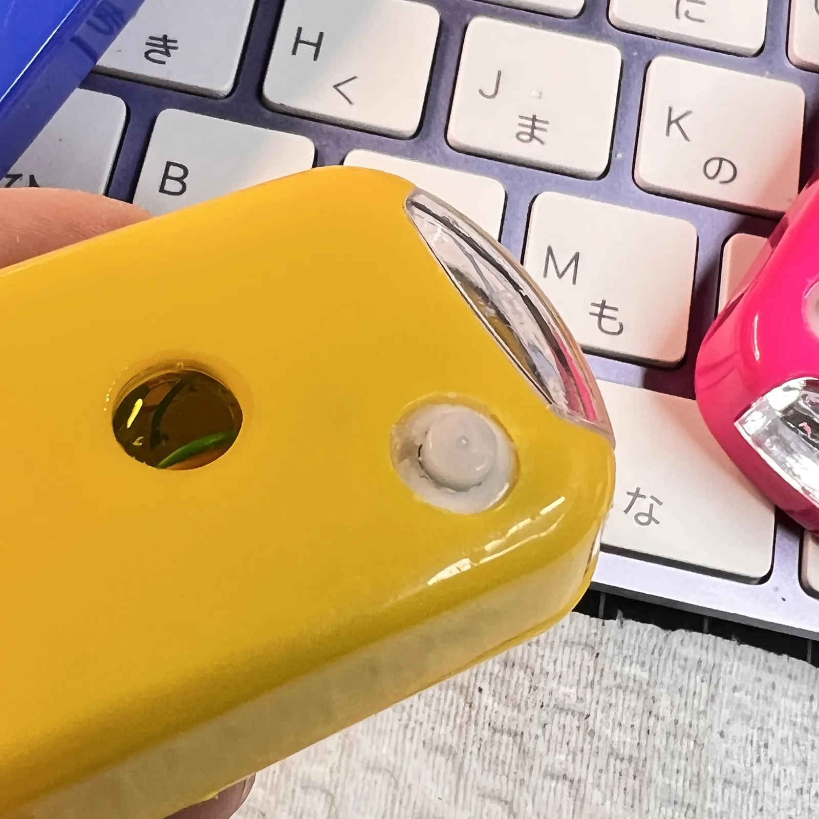 黄色い本体の側面。小さな穴と丸いボタンが見える