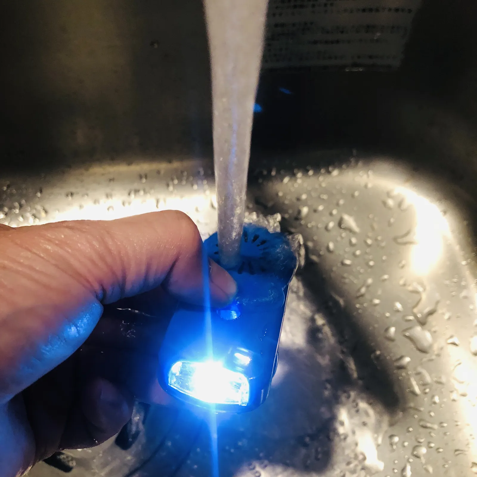 蛇口の水を、光る青い本体にかけて防水を確かめているところ